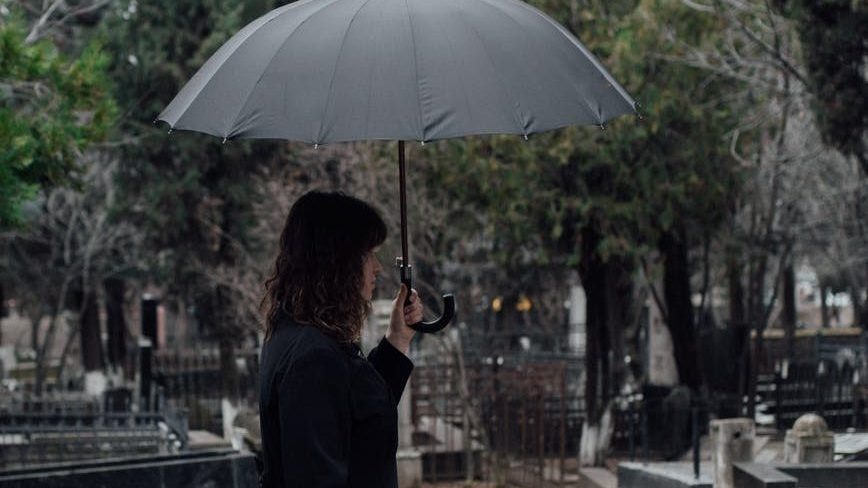 woman in black long sleeves dress holding black umbrella